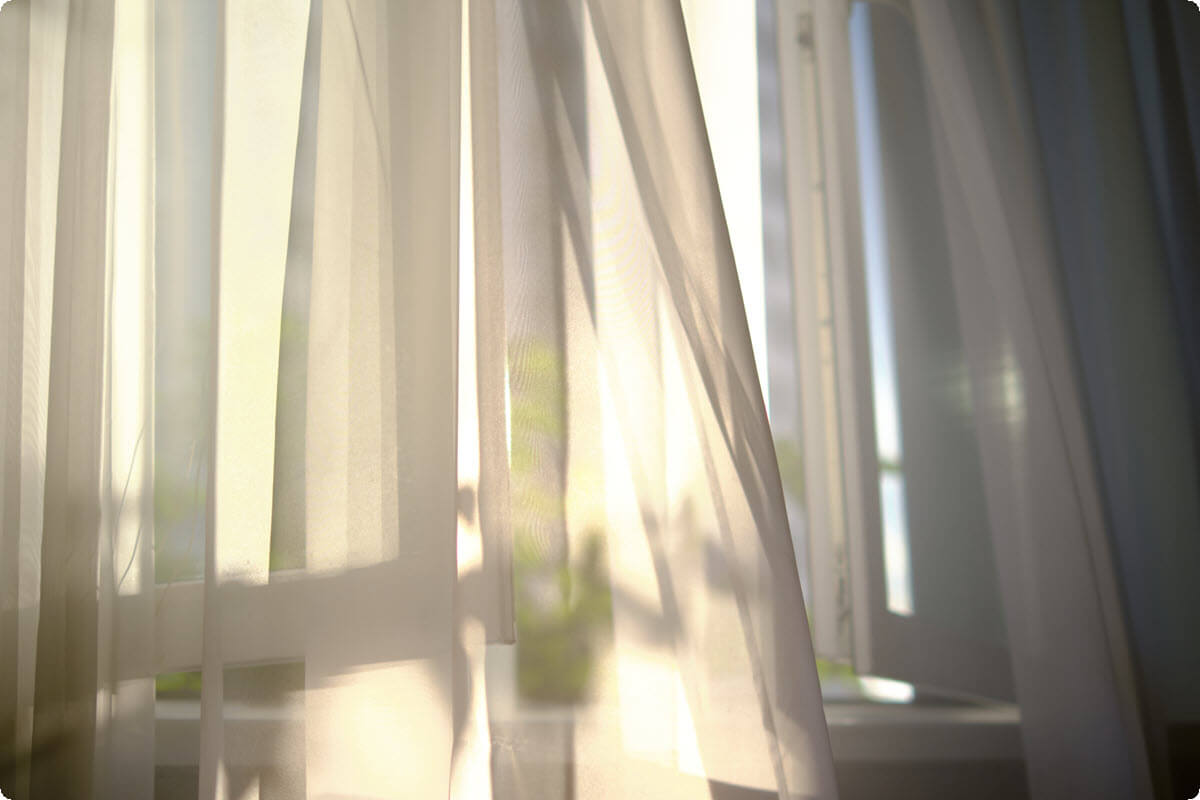 White curtains drifting in soft sunlight near an open window White curtains drifting in soft sunlight near an open window